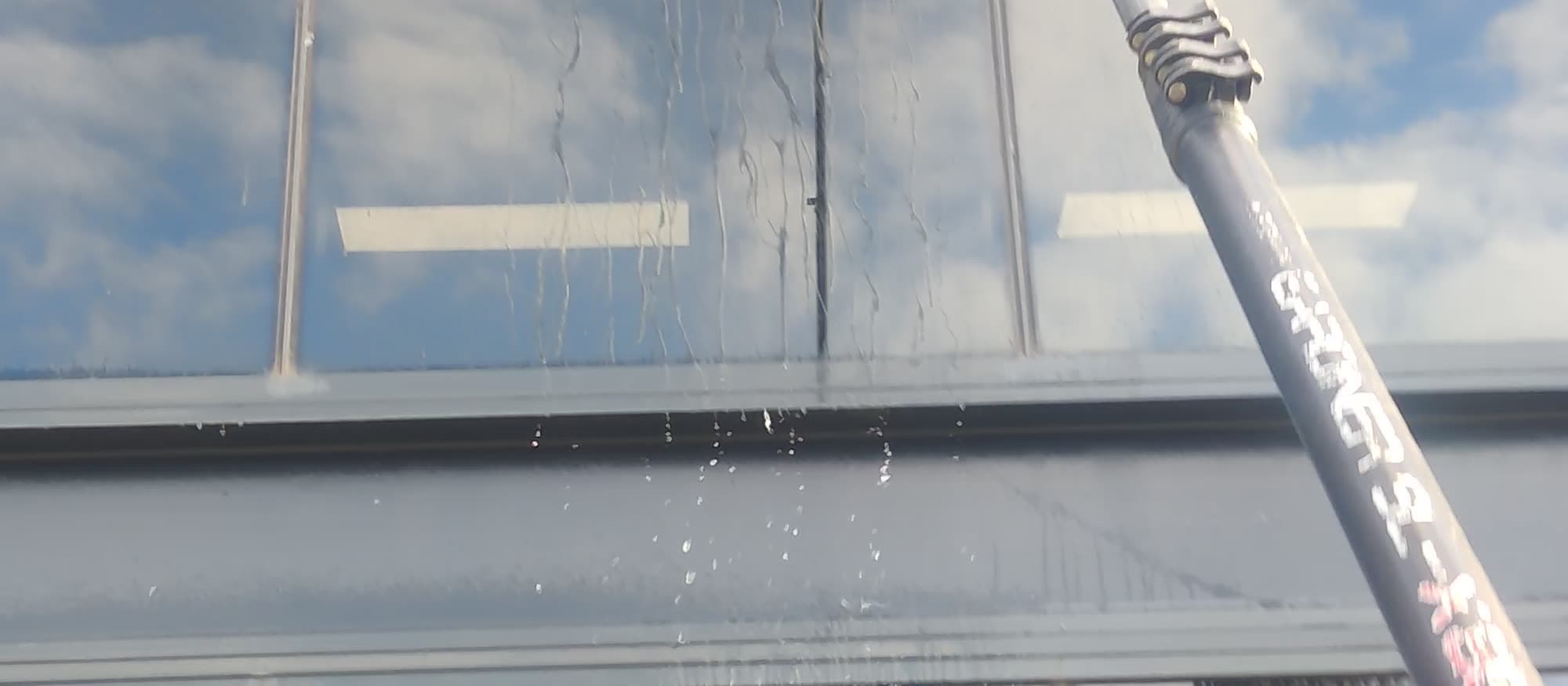 Cleaning a shopfront window with a water-fed pole